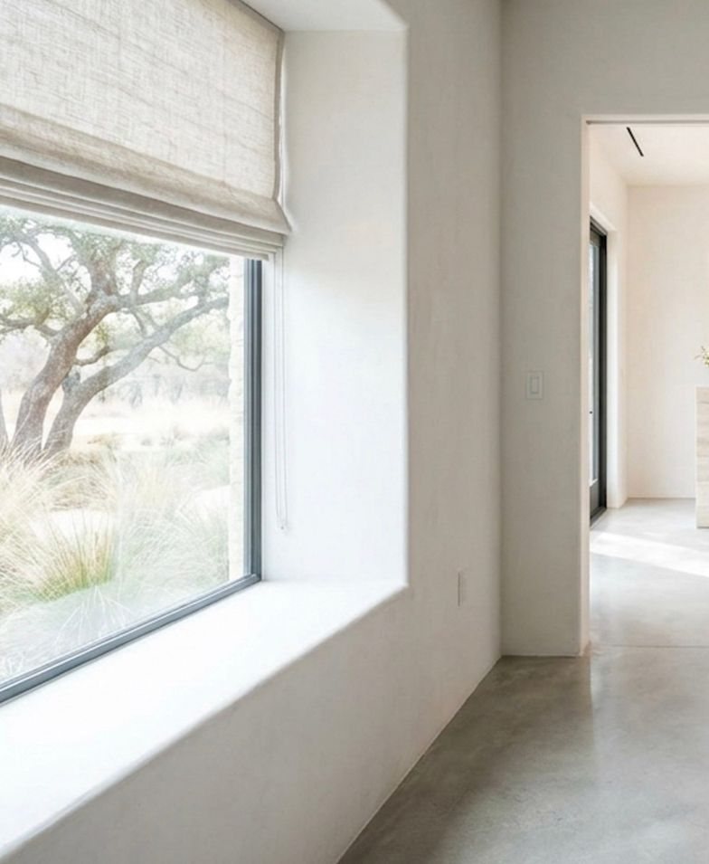 A bright, quiet room with a tall window onto trees and grasses